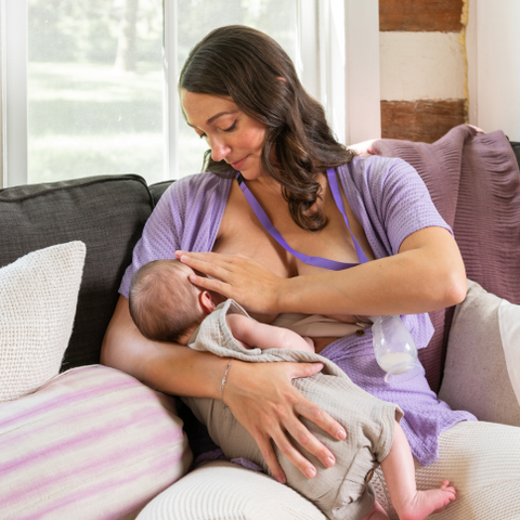 Mom breastfeeding baby while using silicone breastpump or breastmilk collector on the other breast